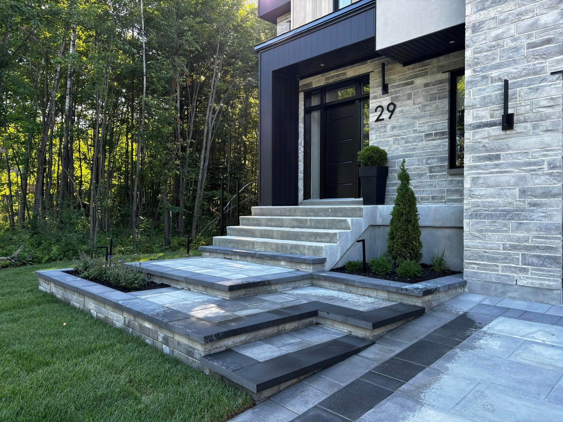 Entrée de maison moderne avec marches en pierre et aménagement paysager. Numéro 29 sur la porte.