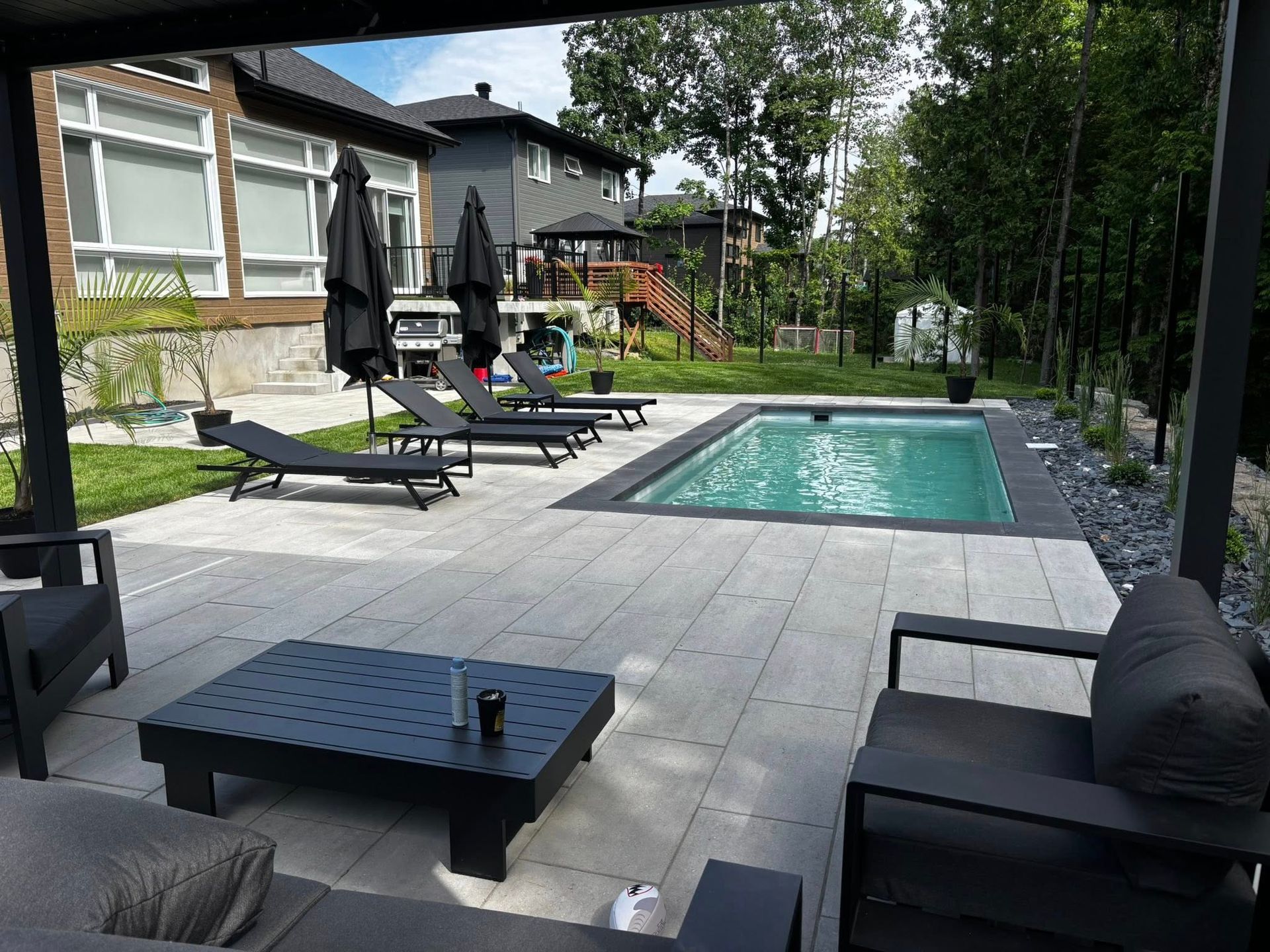 Terrasse arrière avec piscine, chaises longues et mobilier moderne.