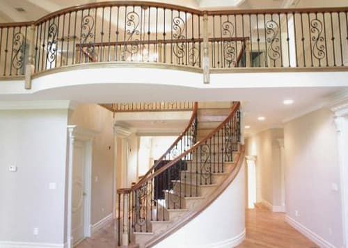 An empty house with a curved staircase and a balcony