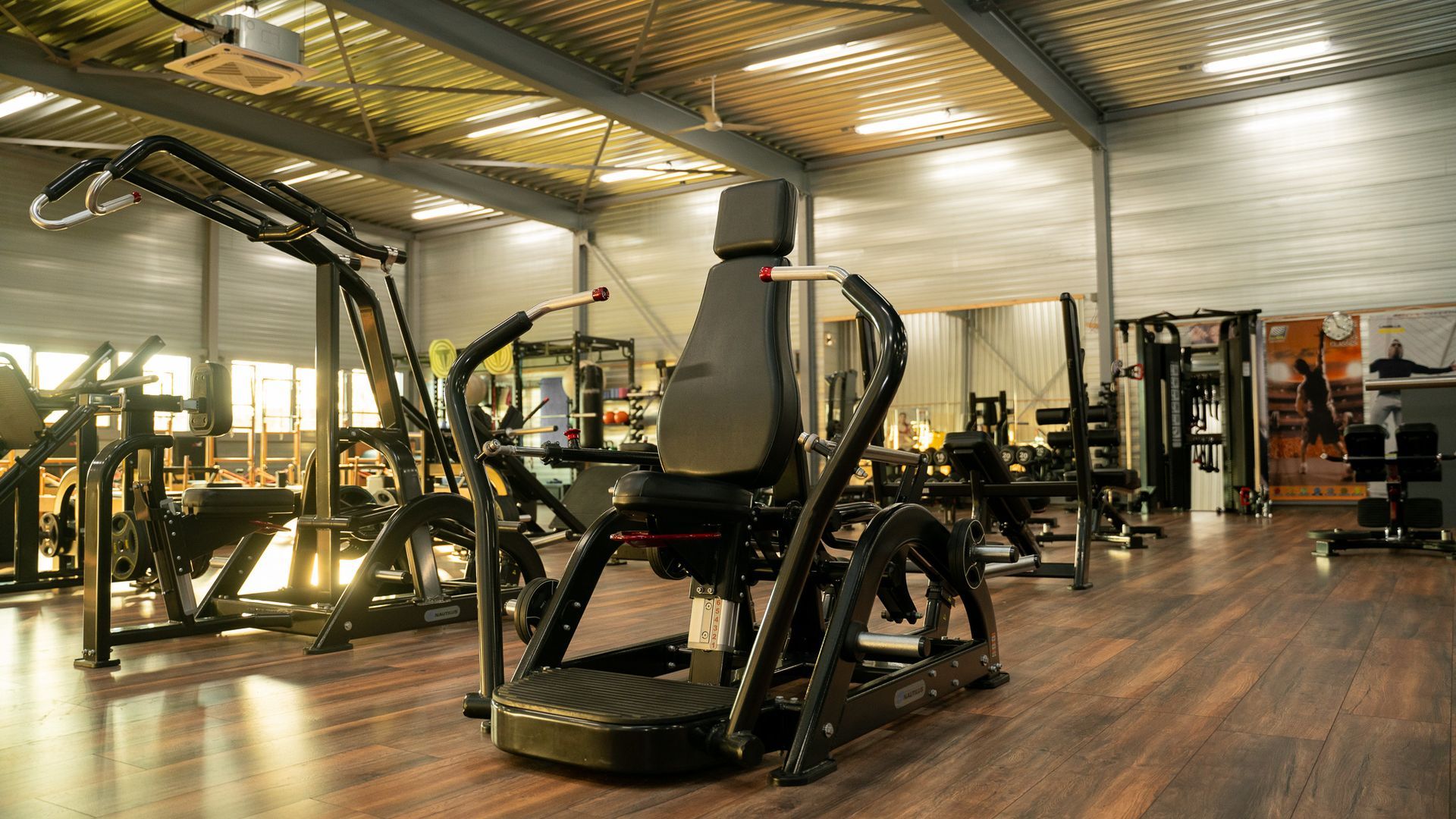 Een sportschool vol met fitnessapparatuur en een stoel.