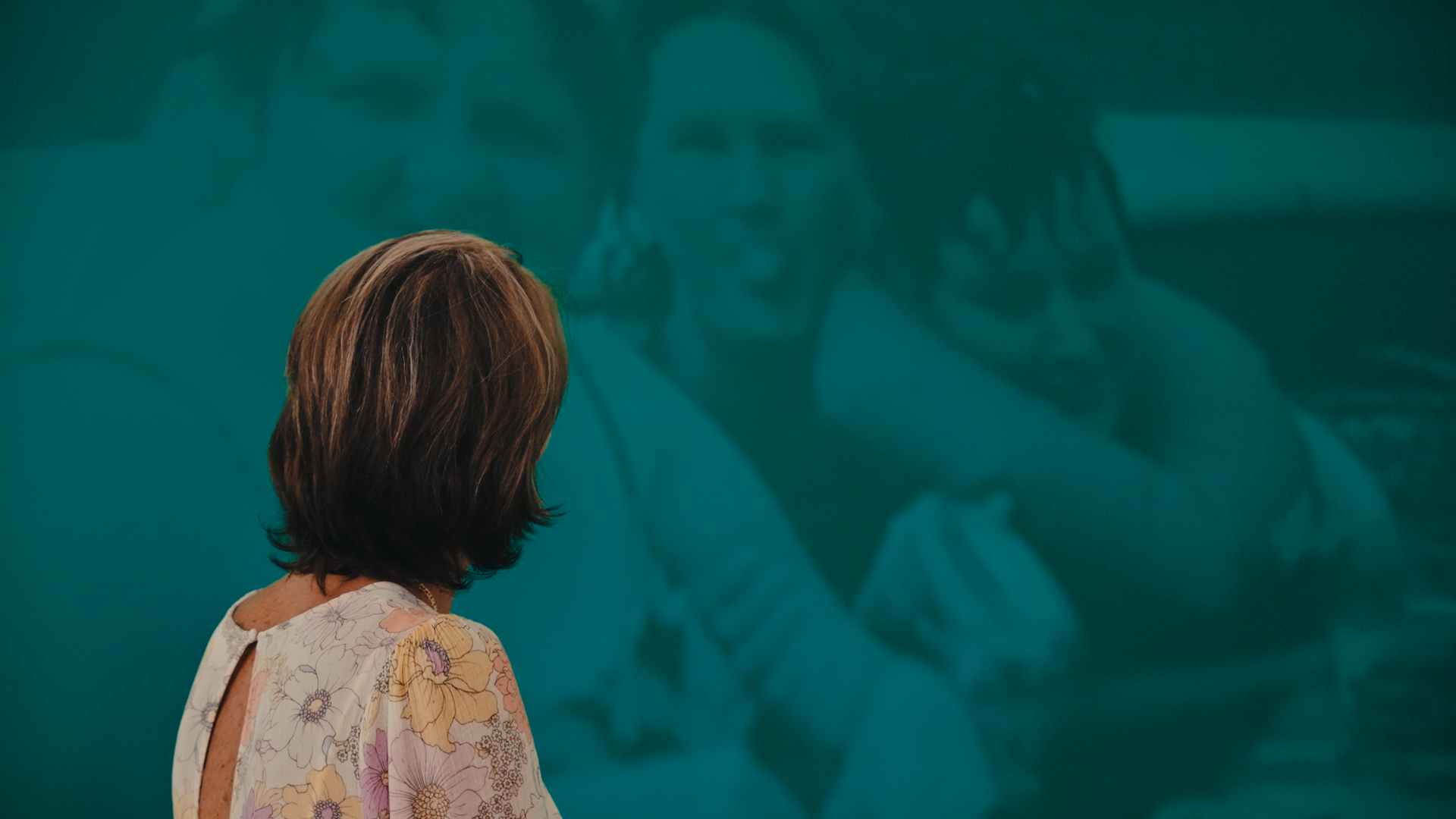 Women looking at the wall behind her as a montage plays on a green wall