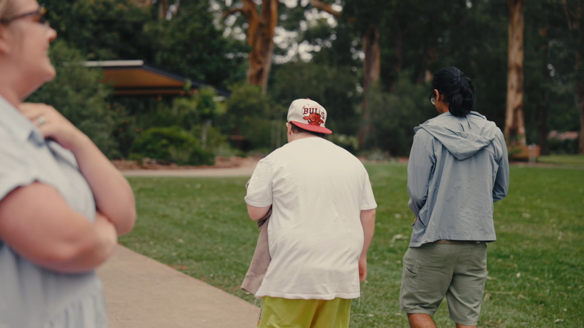 Client and support worker walking into the distance along a paved path in the park