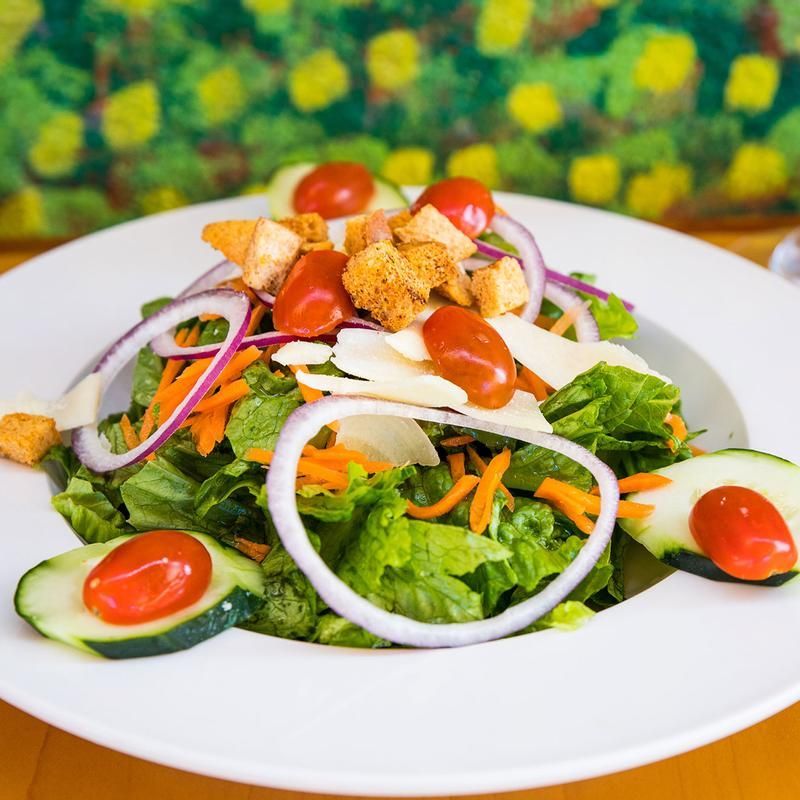A salad with tomatoes onions and cucumbers in a white bowl