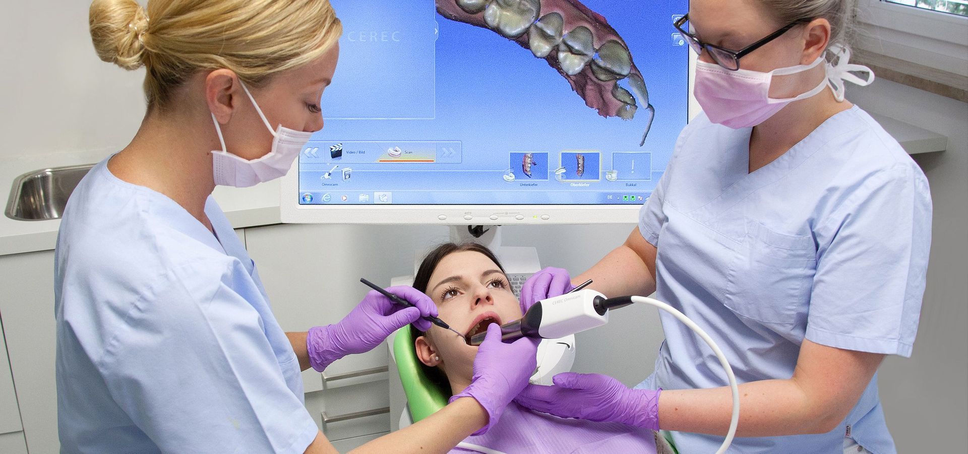 Zwei Zahnärztinnen untersuchen in einer Zahnarztpraxis die Zähne eines Patienten.