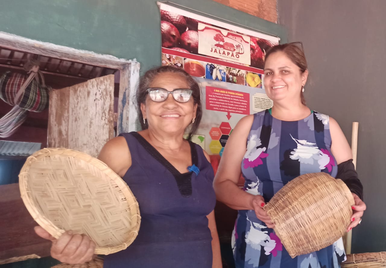 Duas mulheres estão de pé uma ao lado da outra segurando cestas