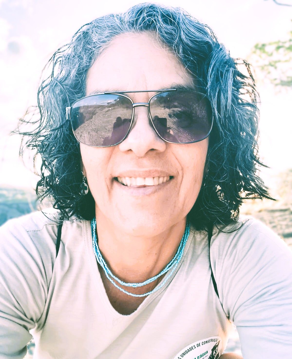 Uma mulher de óculos e camisa verde olha para a câmera