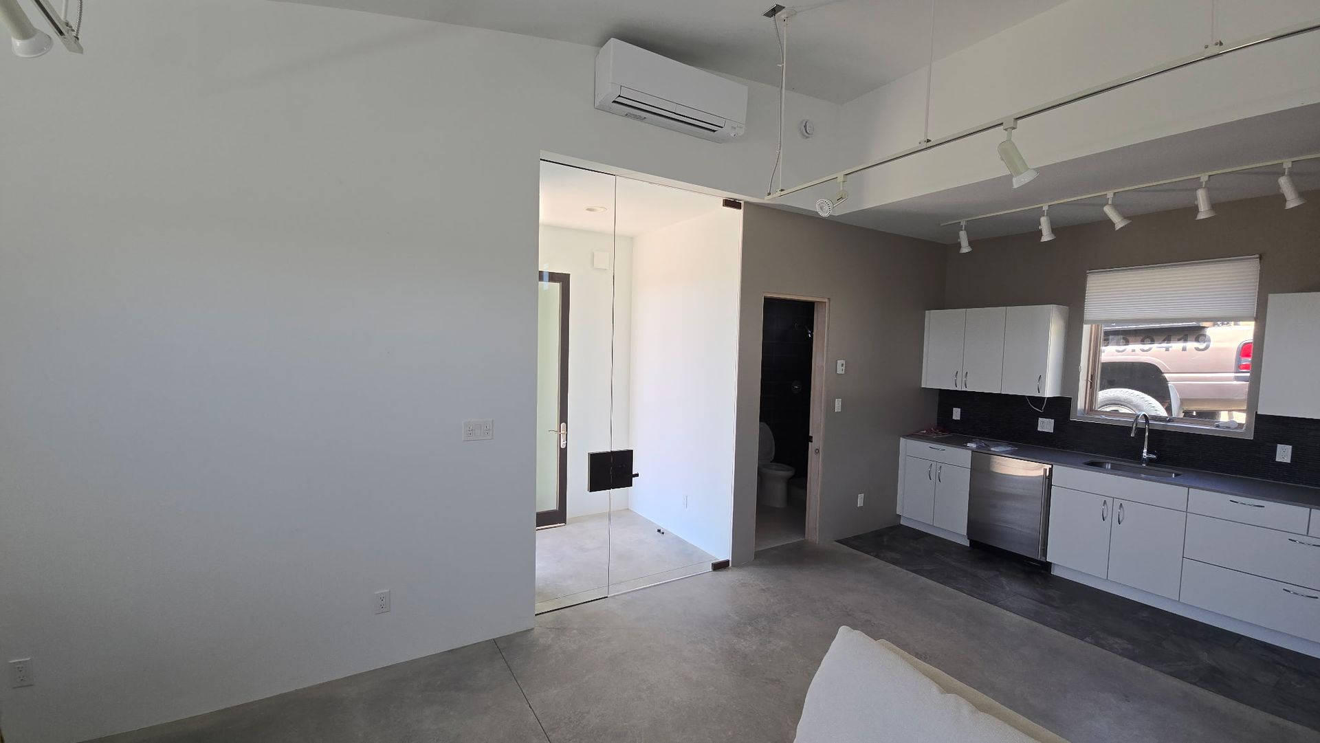 Modern apartment interior with kitchen, bathroom, and gray walls.