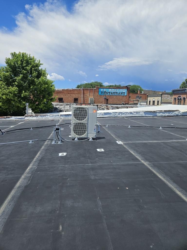 Rooftop view of an HVAC unit, overcast sky, buildings in the distance.