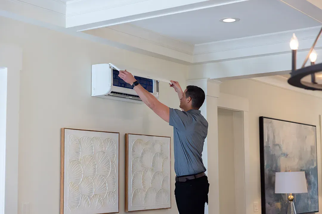 Technician opening cover of wall-mounted unit for service or repair.