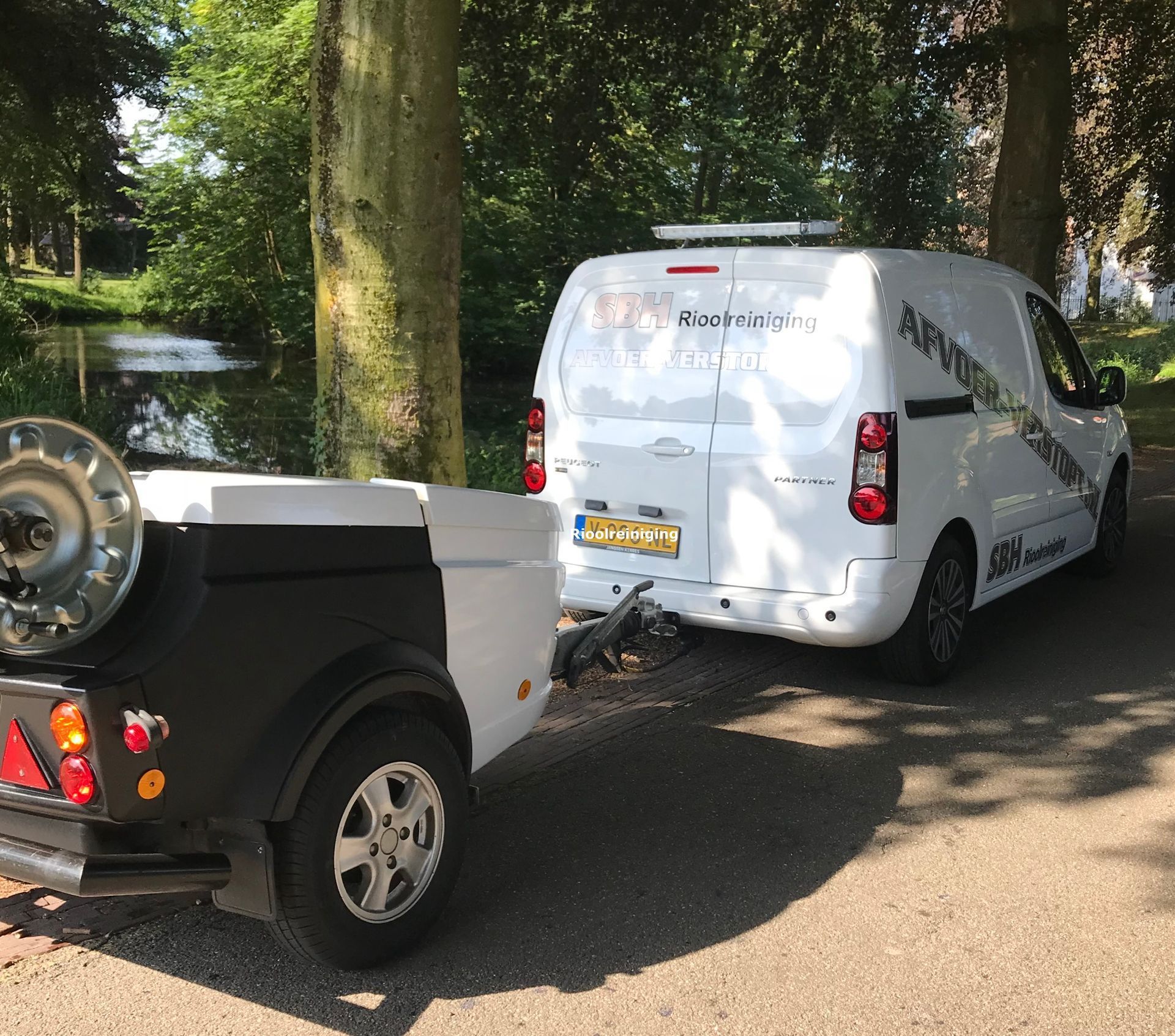 Bedrijfswagen met aanhanger en hogedrukinstallatie voor rioolreiniging