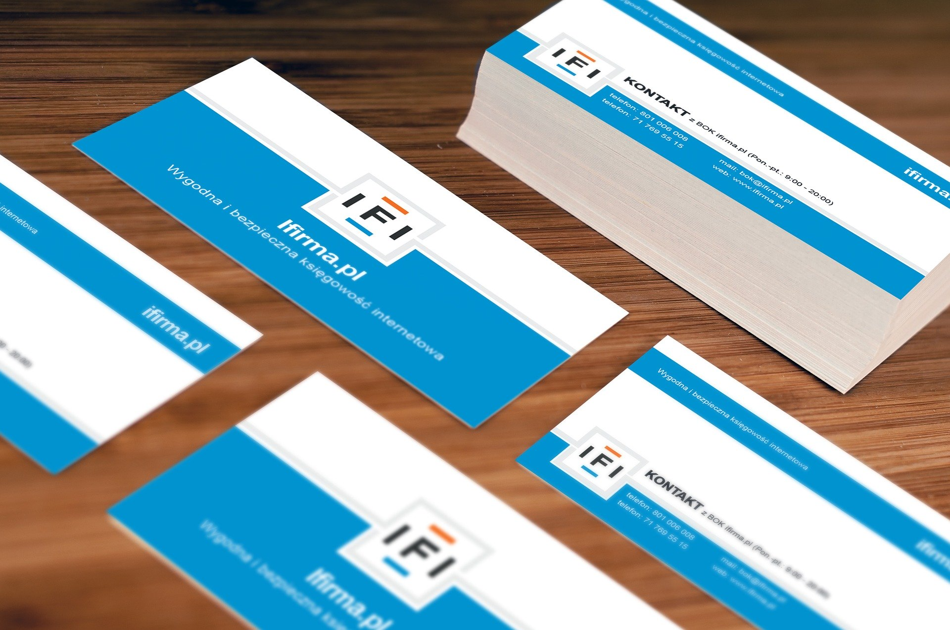 Business cards with blue and white design, stacked on a wooden surface.