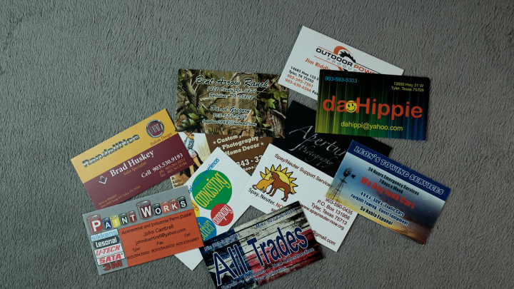 Pile of colorful business cards on a grey surface, featuring company logos and contact information.