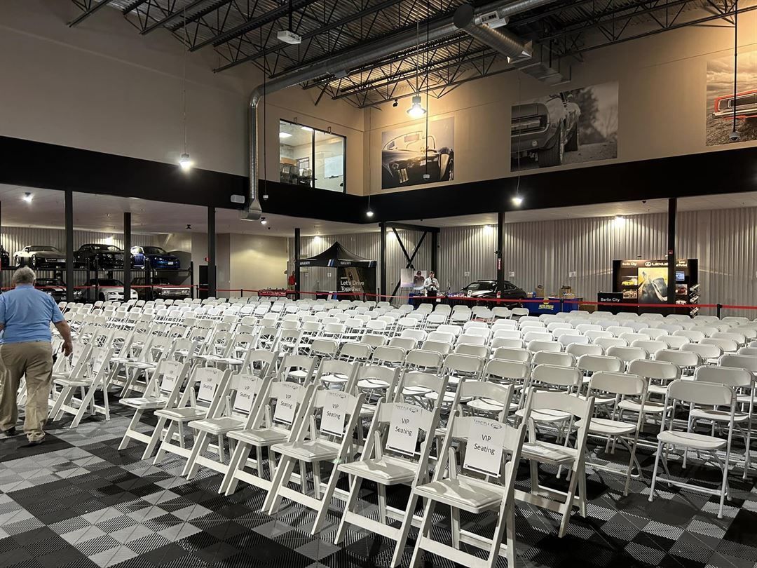 A large room filled with rows of white folding chairs.