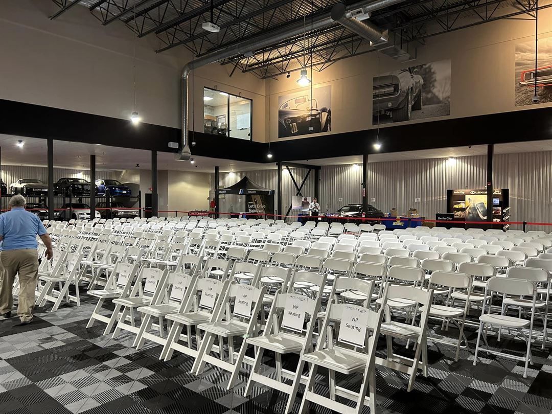 A large room filled with rows of white folding chairs.