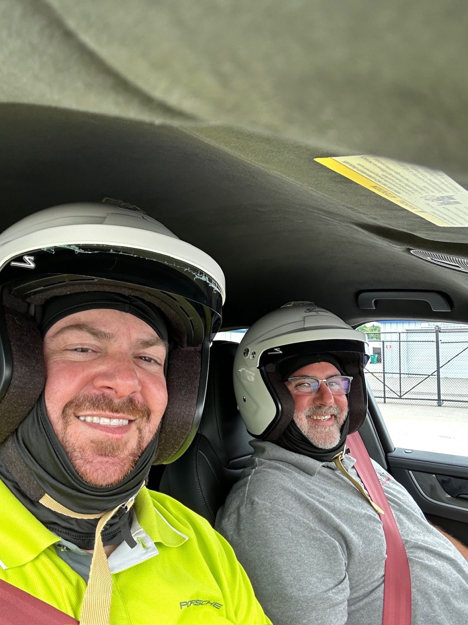 Two men wearing helmets are sitting in a car.