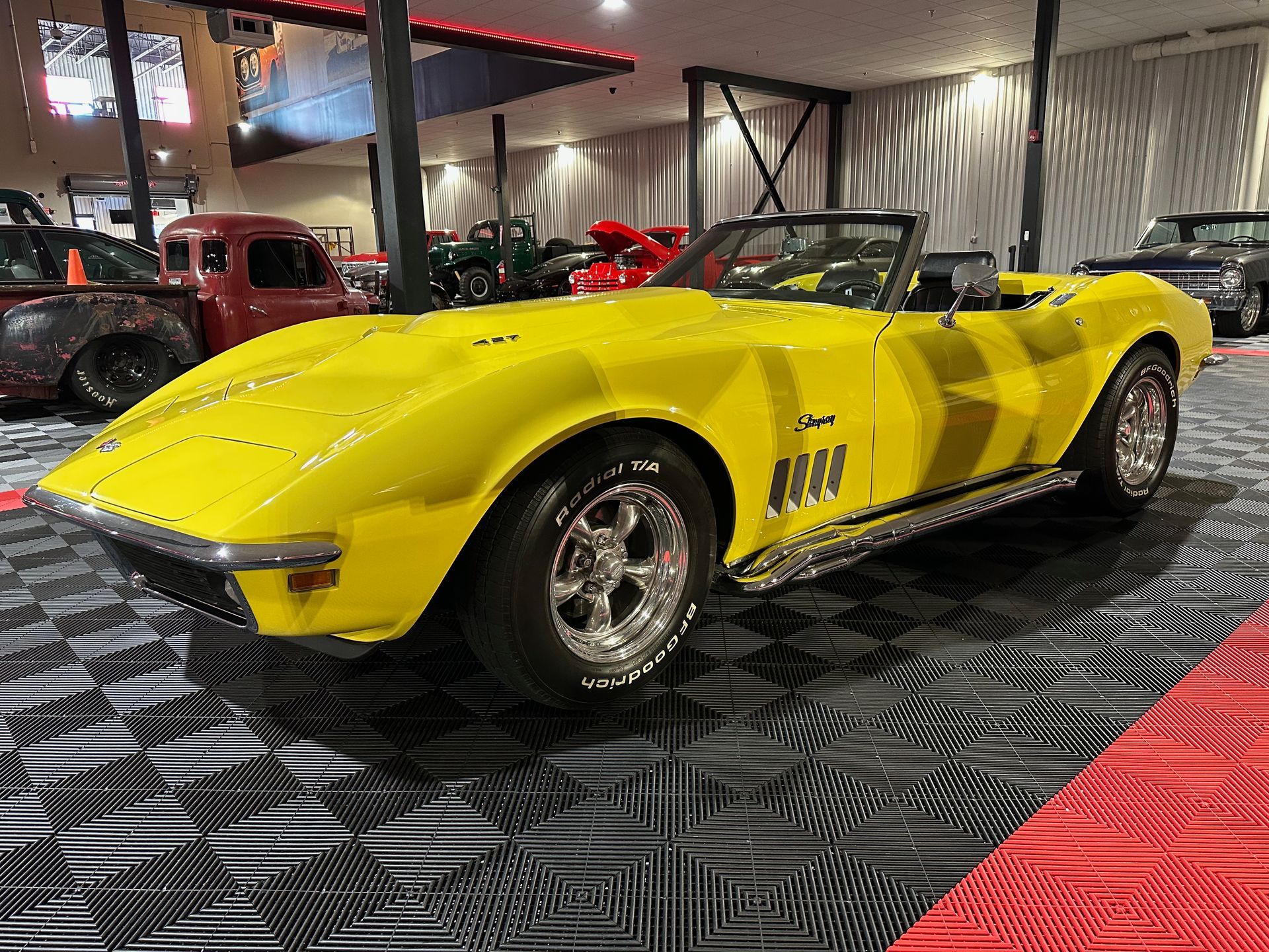 A yellow corvette convertible is parked in a garage.