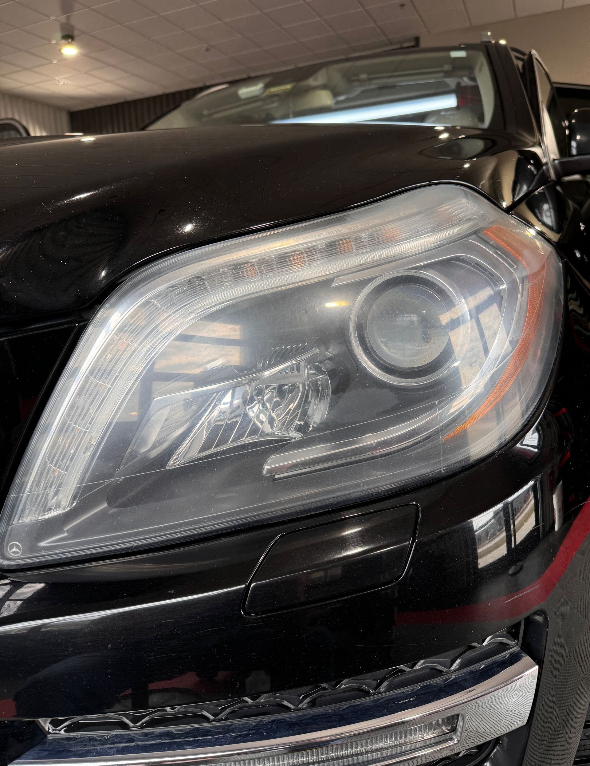 A close up of a black car 's headlight in a garage.