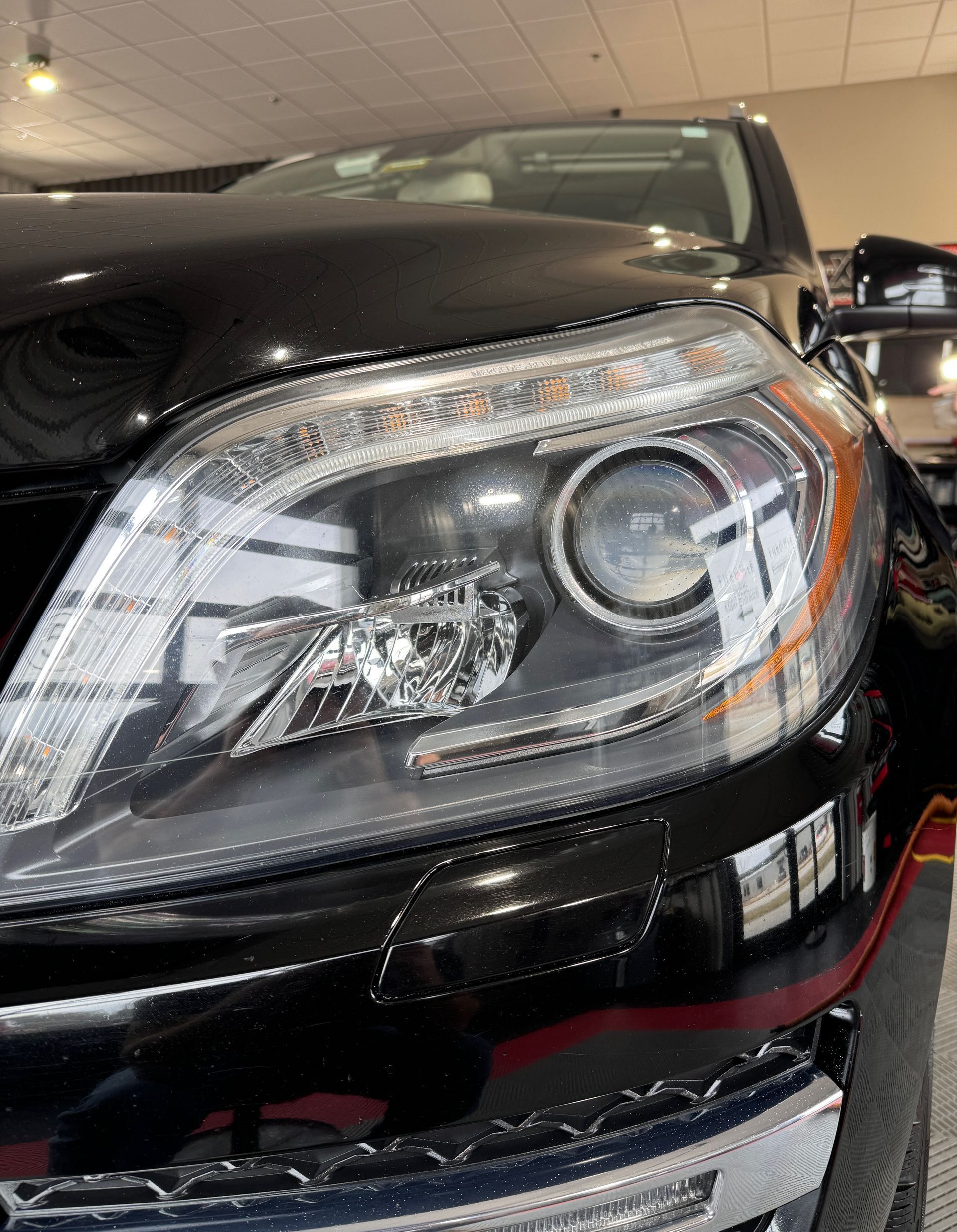 A close up of a black car 's headlight in a garage.