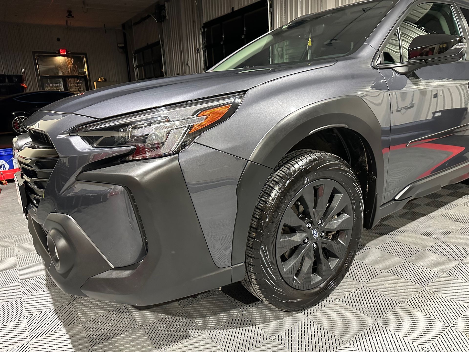A gray subaru outback is parked in a garage.