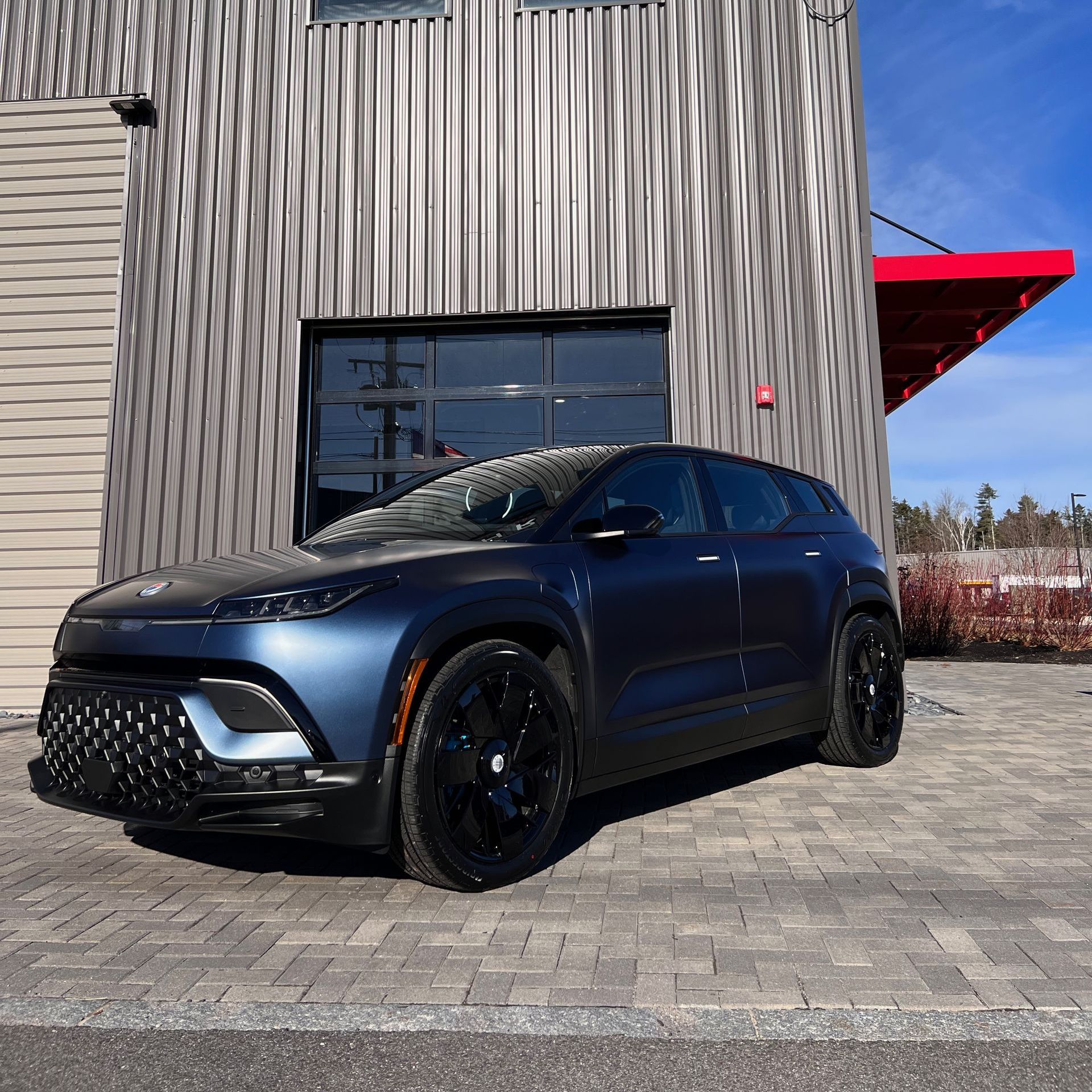 A blue car is parked in front of a building that says throttle.