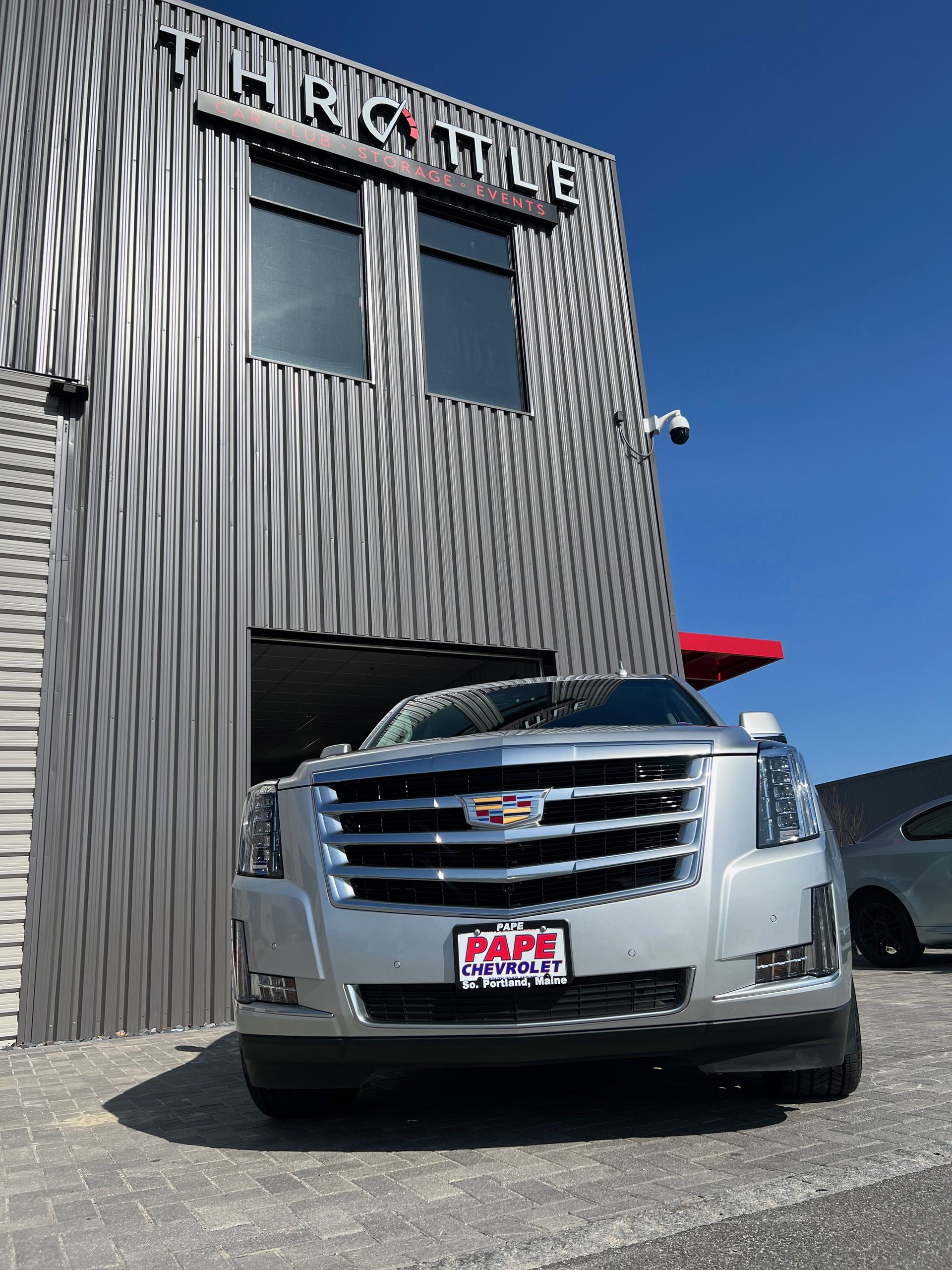 A silver car is parked in front of a building that says throttle
