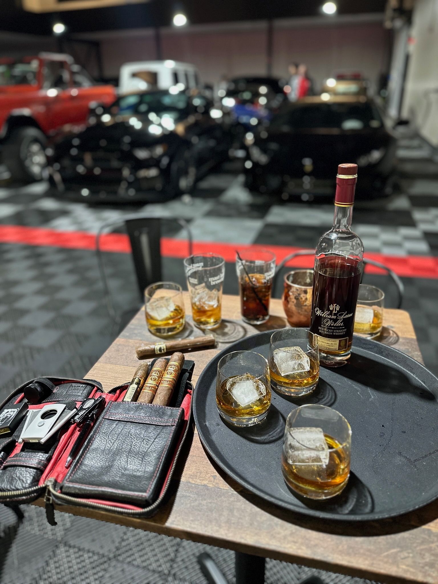 A table with a tray of whiskey and cigars on it.