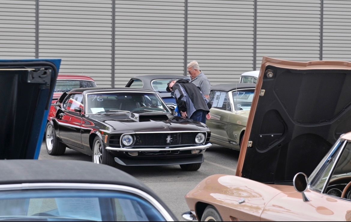 A man is opening the hood of a black mustang