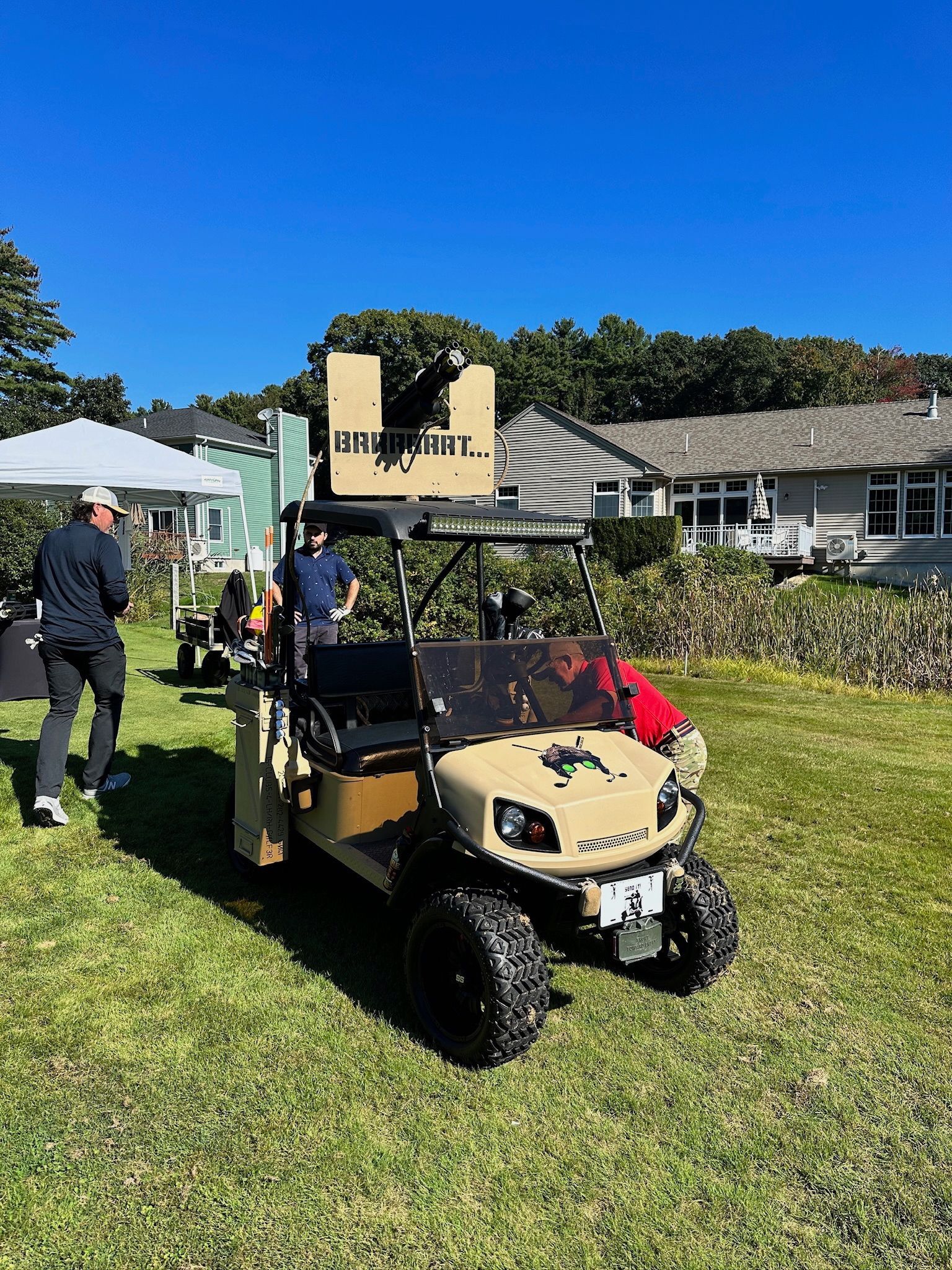 A golf cart with a cannon on top of it is parked in a grassy field.