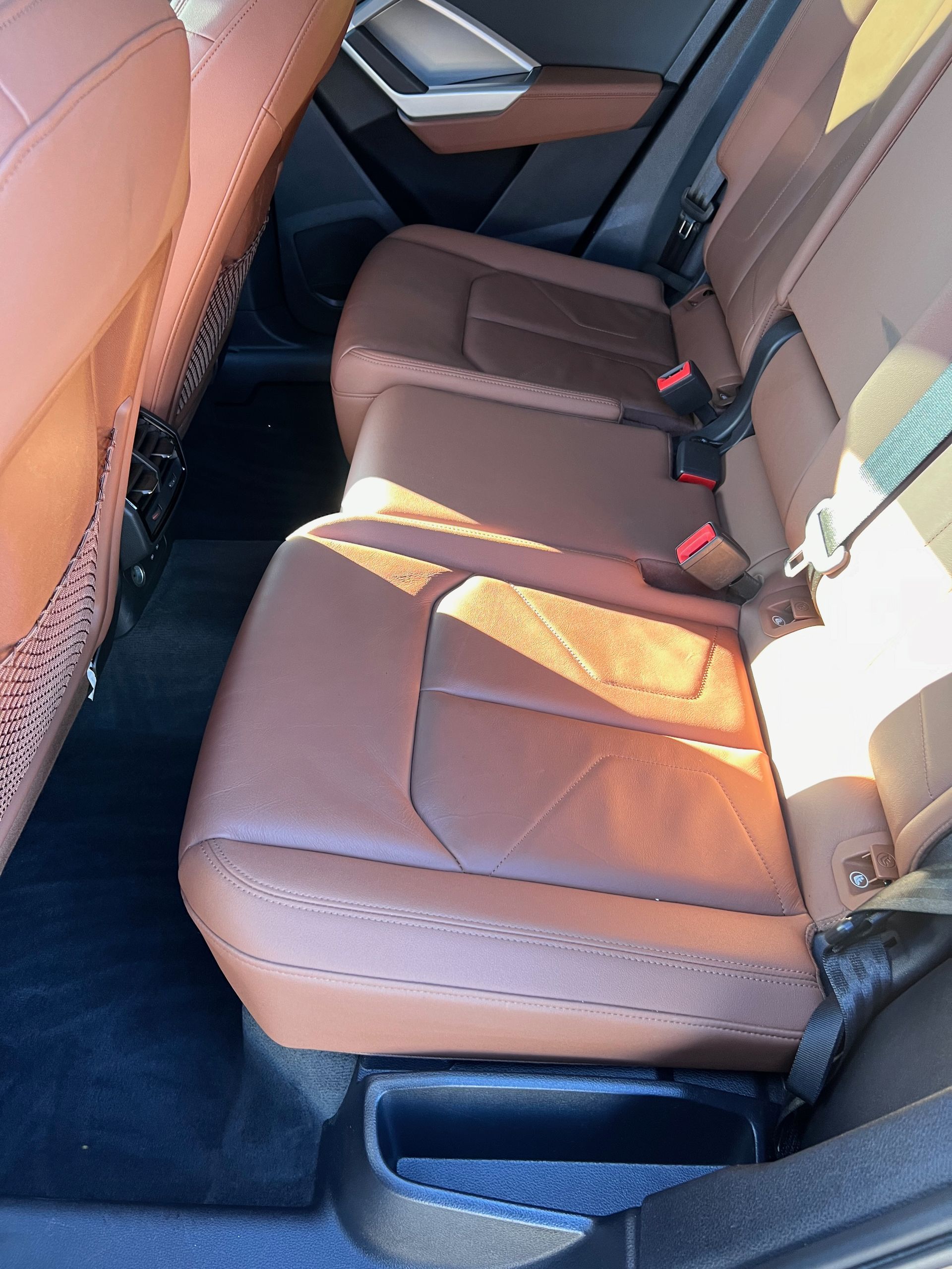 The back seat of a car with brown leather seats.