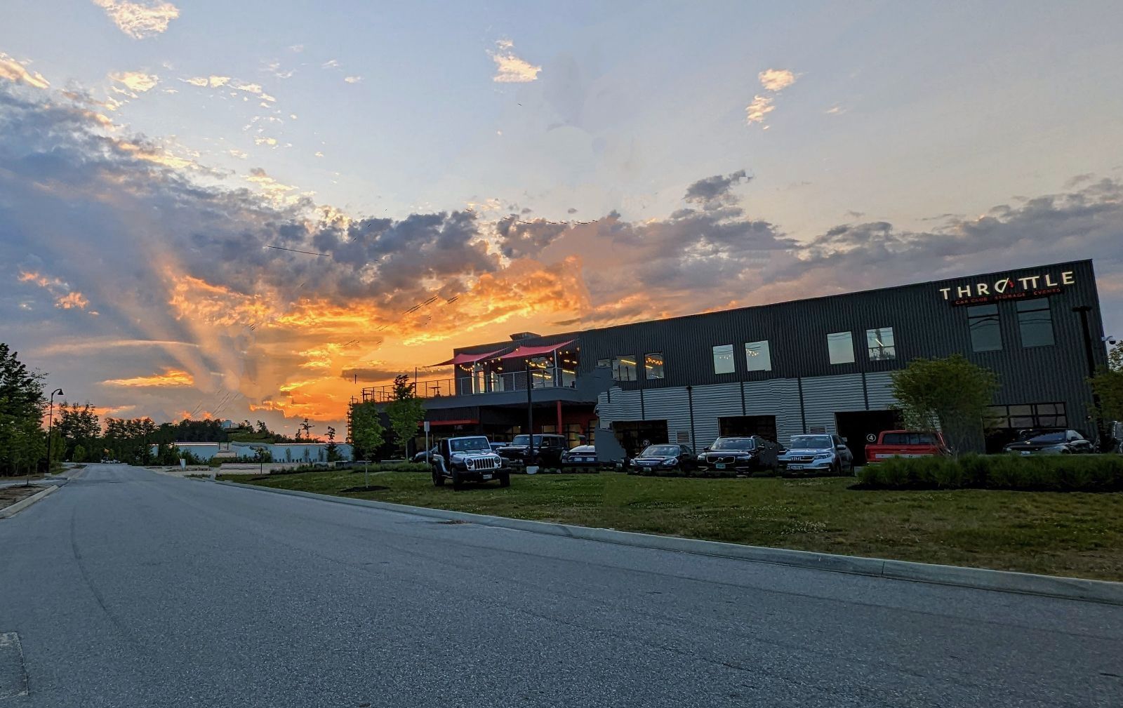 A large building with cars parked in front of it at sunset.