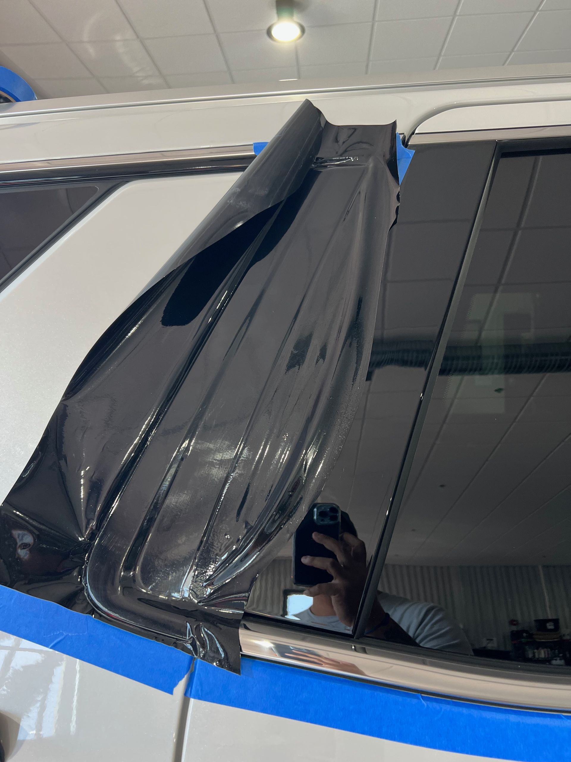 A person is taking a picture of a car with a cell phone.