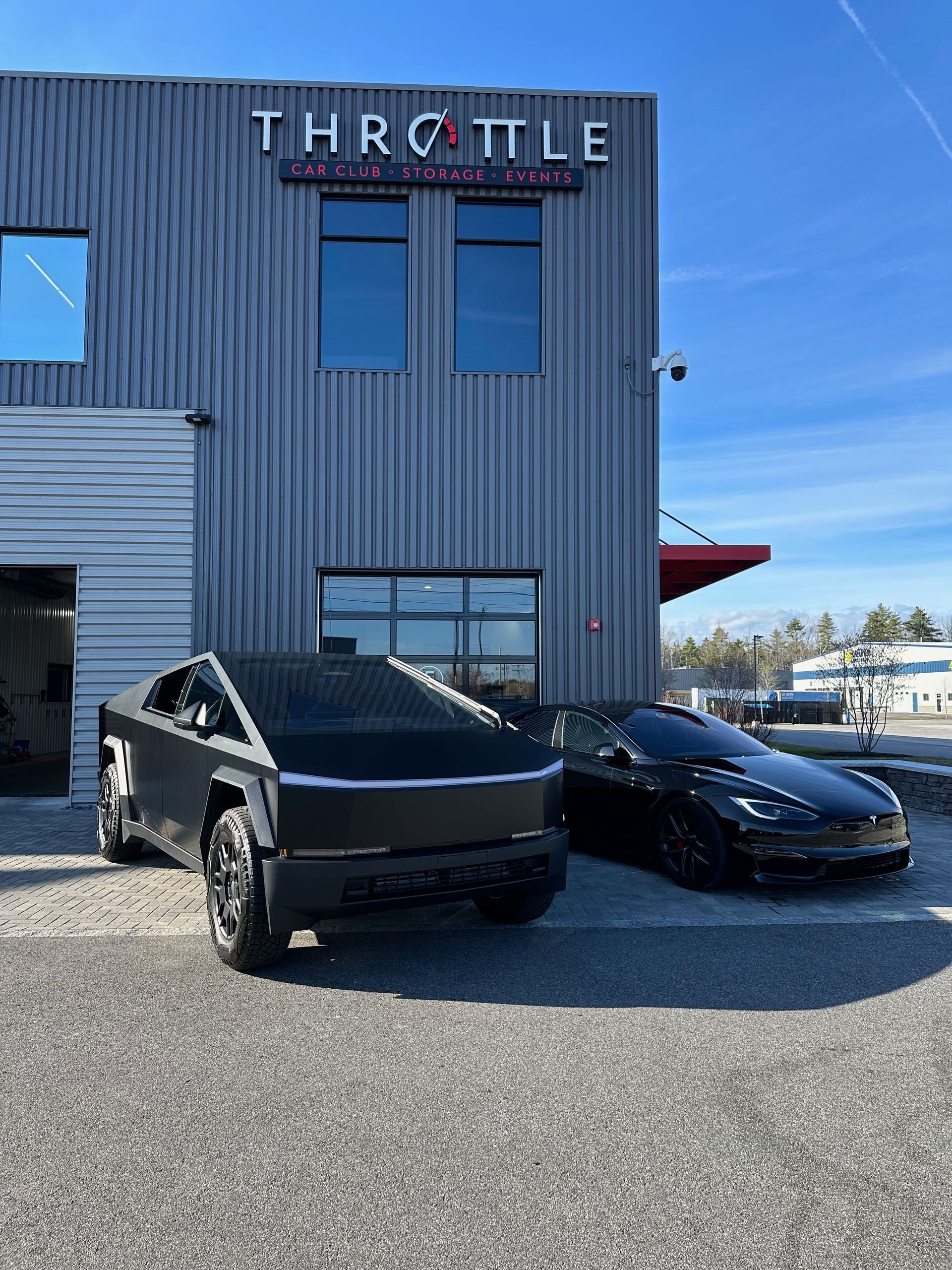 Two tesla cars are parked in front of a building.