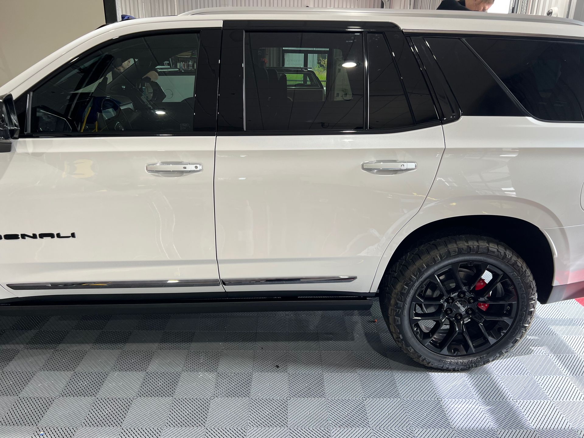 A white suv with black wheels is parked on a tiled floor.