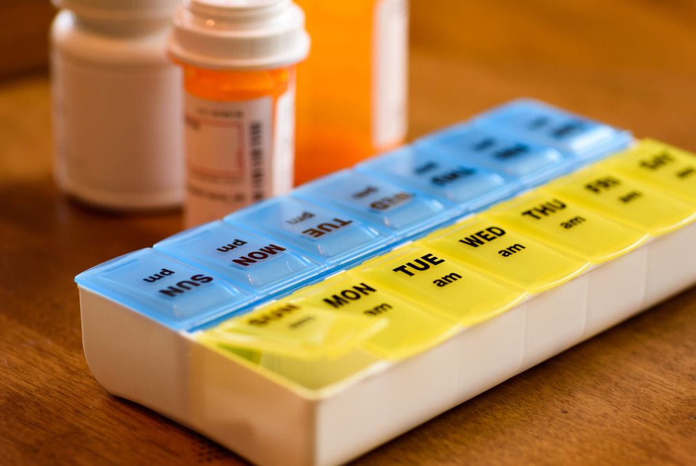 Several bottles of pills are sitting on a table next to a pill organizer