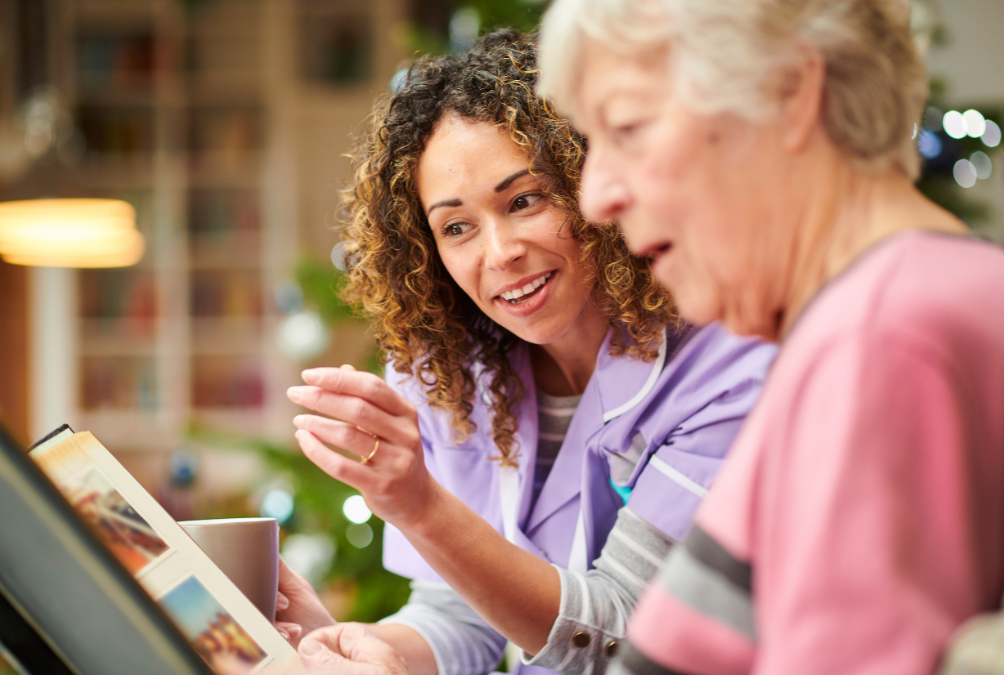A nurse is teaching an elderly woman how to use a computer.