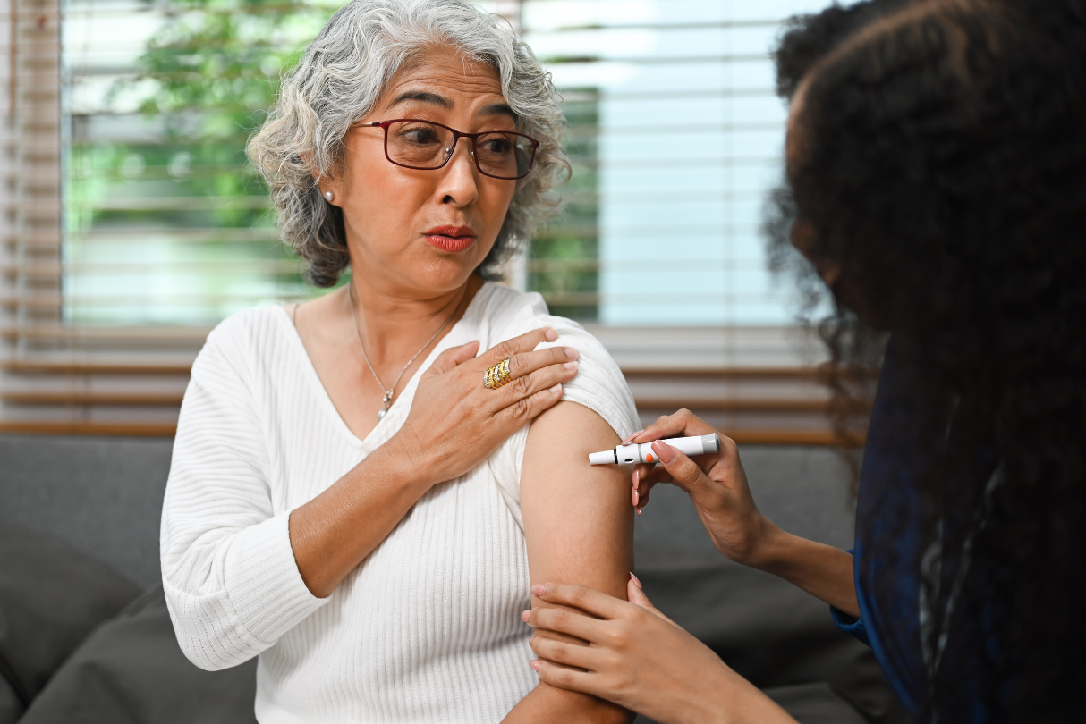 An elderly woman is getting an injection in her arm.