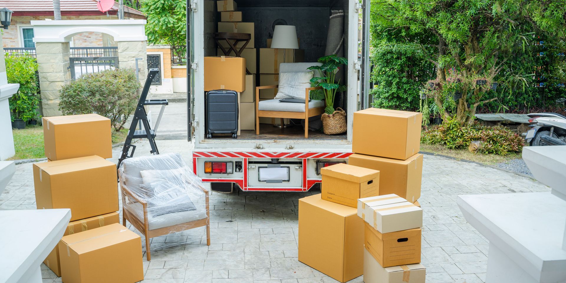 Moving truck loaded with boxes and furniture on a driveway.
