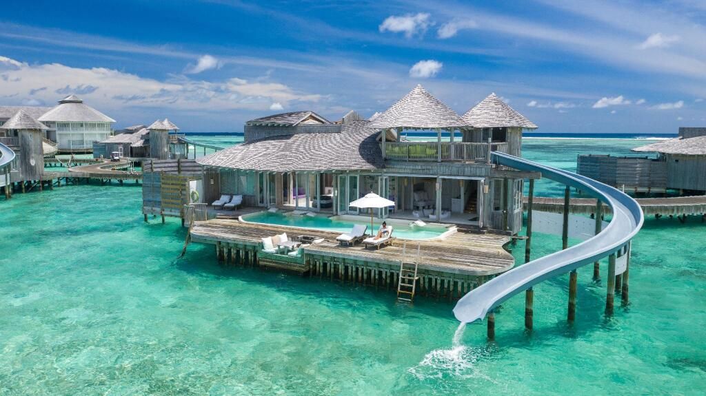 Overwater villas with private slides at a luxury Maldives resort, ideal for First & Business Class flight and hotel packages - xLuxuryFlights.com