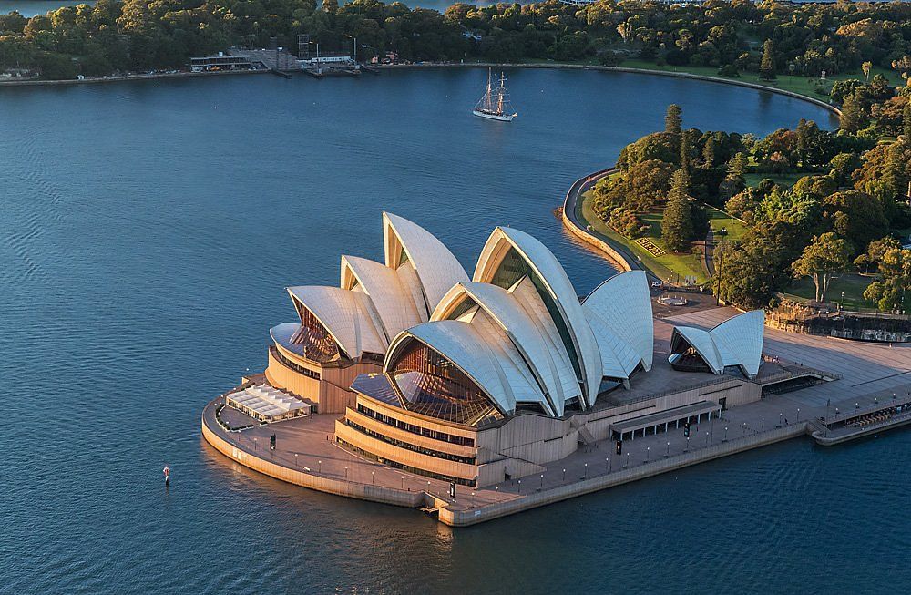 Bird’s-eye harbour view of the Sydney Opera House surrounded by water, a 5-star city destination ideal for premium First & Business Class Flight + Hotel holidays - xLuxuryFlights.com