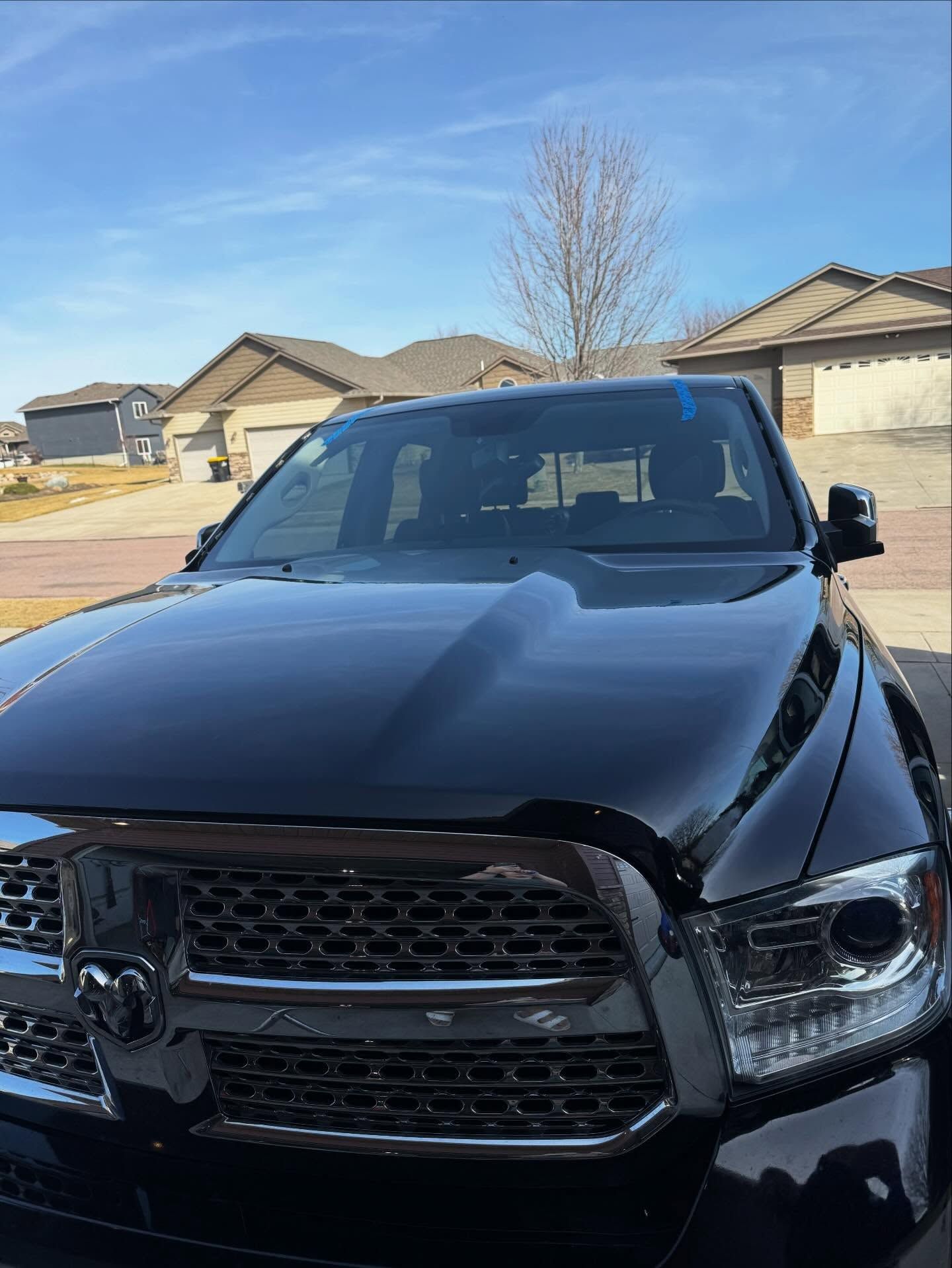 A black Dodge Ram pickup truck parked on a residential street during a sunny day.