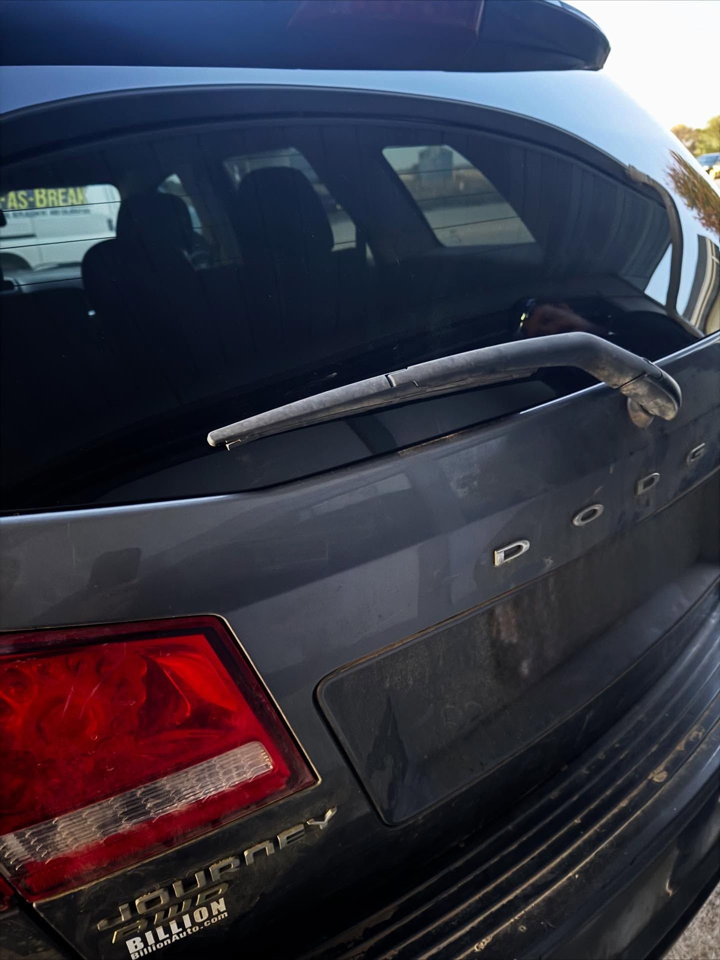 Rear view of a grey Dodge Journey SUV with a visible windshield wiper and taillight.