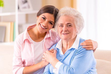 A young woman is hugging an older woman on a couch.