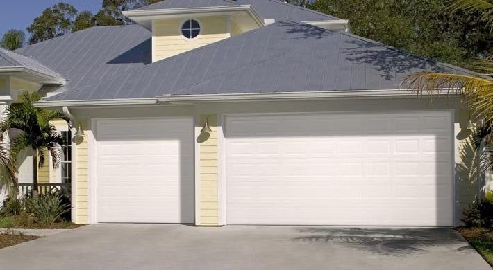 Suburban house with a two-car garage and a single side door, viewed from the driveway.