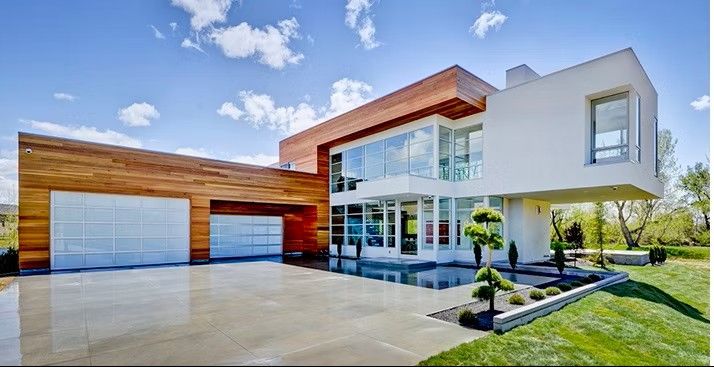 Modern two-story house with wood and white exterior, large garage, and landscaped front yard under a blue sky