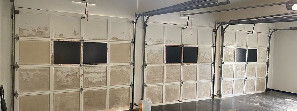 Interior room with exposed insulation walls, black window openings, and a coiled cable hanging from the ceiling.