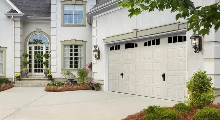 White suburban house exterior with arched entryway, double garage, and landscaped front walkway