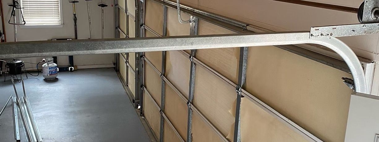 Industrial walkway with beige wall panels, metal railings, and overhead piping.