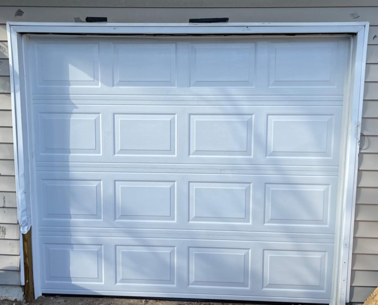White garage door with four-panel windows on a light beige house exterior.
