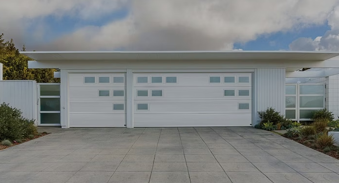 Modern white single-story house with a wide two-car garage and a paved driveway