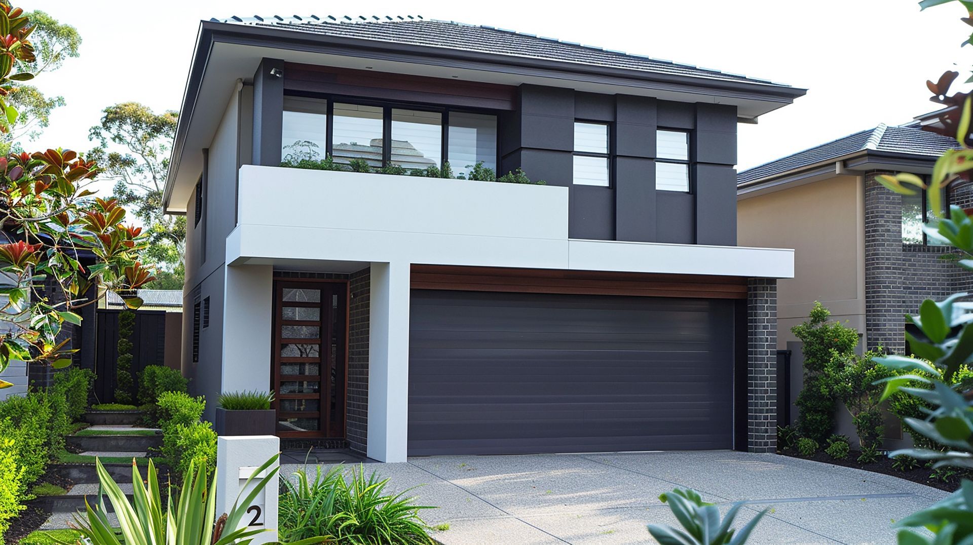 Modern two-story house with white and dark gray exterior, black garage door, and landscaped front yard